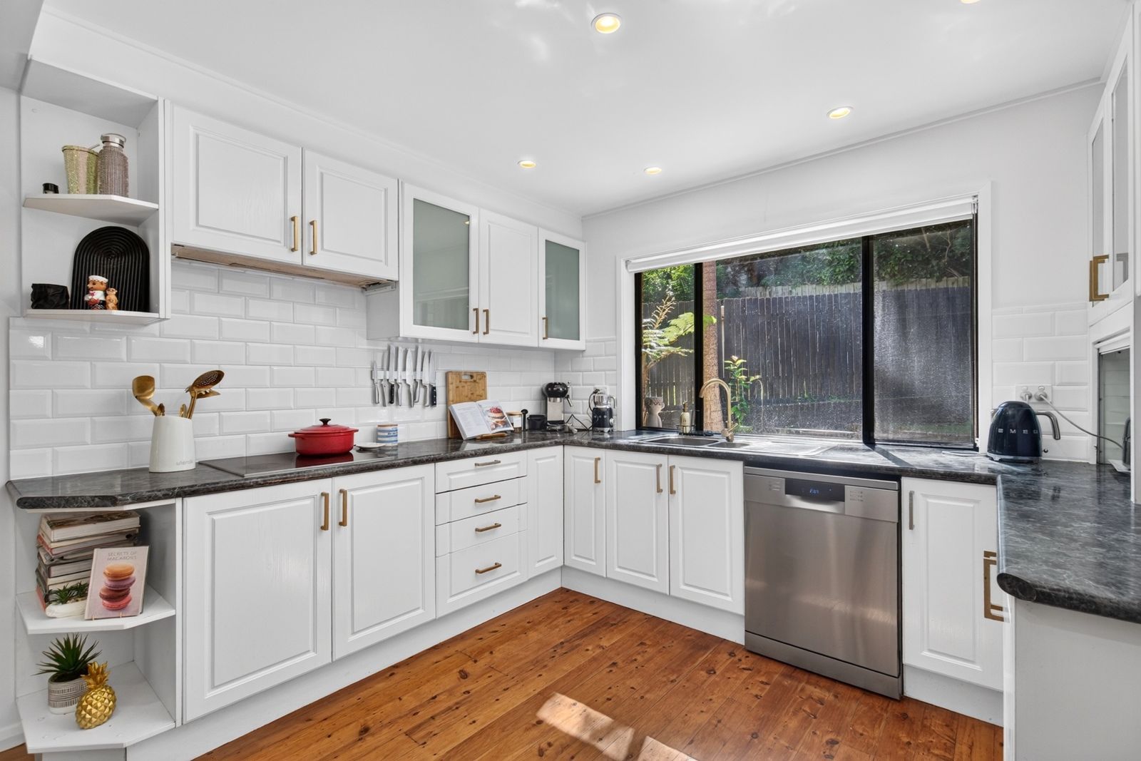 White kitchen with subway tiles, timber floors, a magnetic knife rack and a coffee machine on the bench
